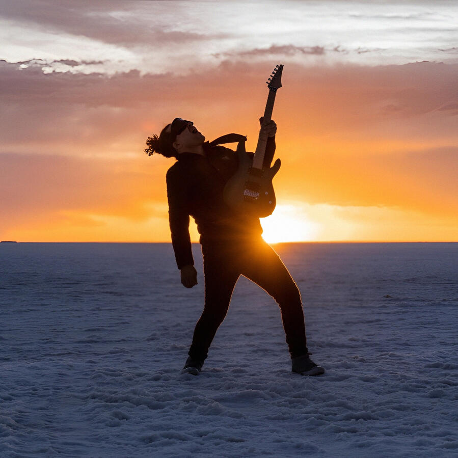 Everton Vidal Azevedo silhouette with guitar at sunset on the Salar de Uyuni. Photo by Marvin Montes.