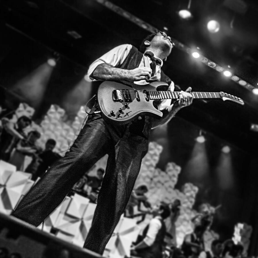 Everton Vidal Azevedo performing a guitar solo with the Camerata del Oriente, Orquesta Municipal de Santa Cruz de la Sierra, black-and-white stage photo. Photo by Antonio Dávila.