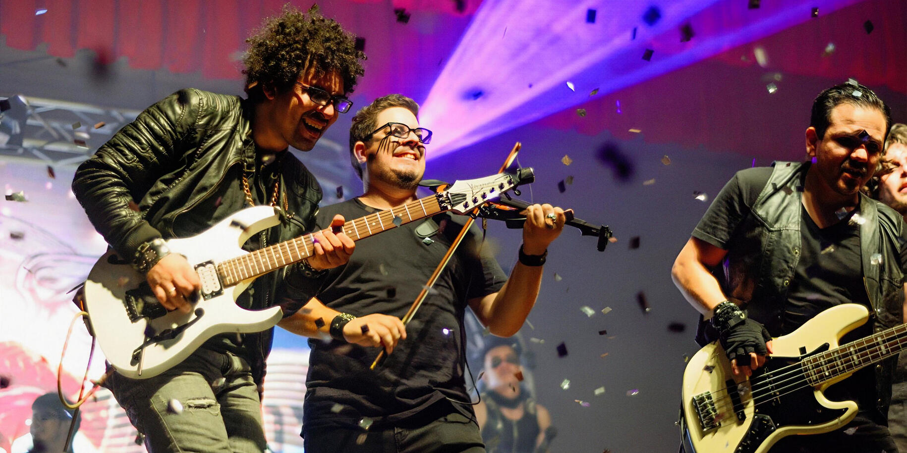 Everton Vidal Azevedo onstage performing with bassist Dorian Méndez and violinist Claudio Arduz, Rodrigo Roca, captured during a high-energy live show. Photo by Rodrigo Roca.