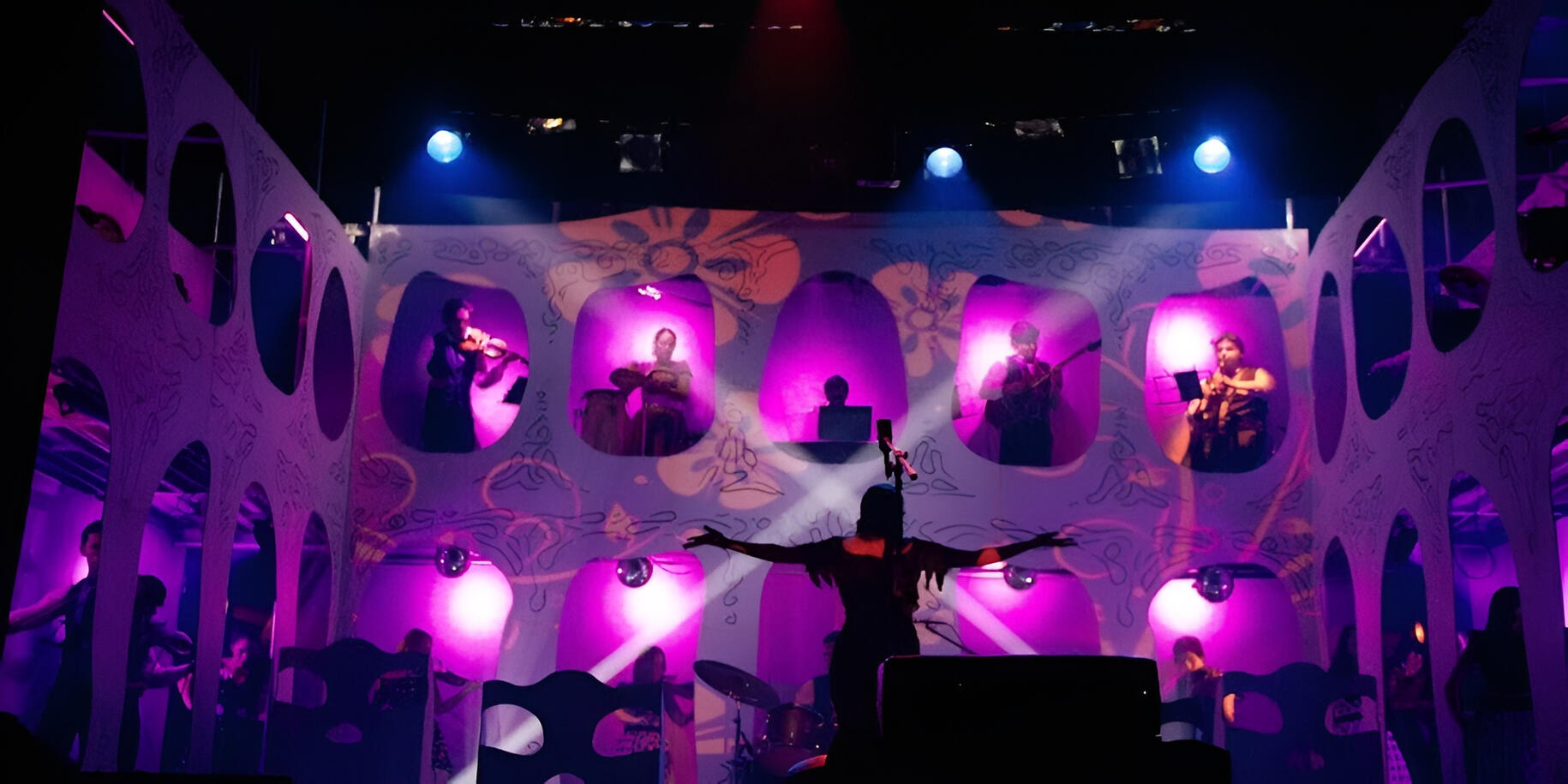 Everton Vidal Azevedo performing with the Camerata del Oriente in a stage production with illuminated multi-window set design (Cambópera).