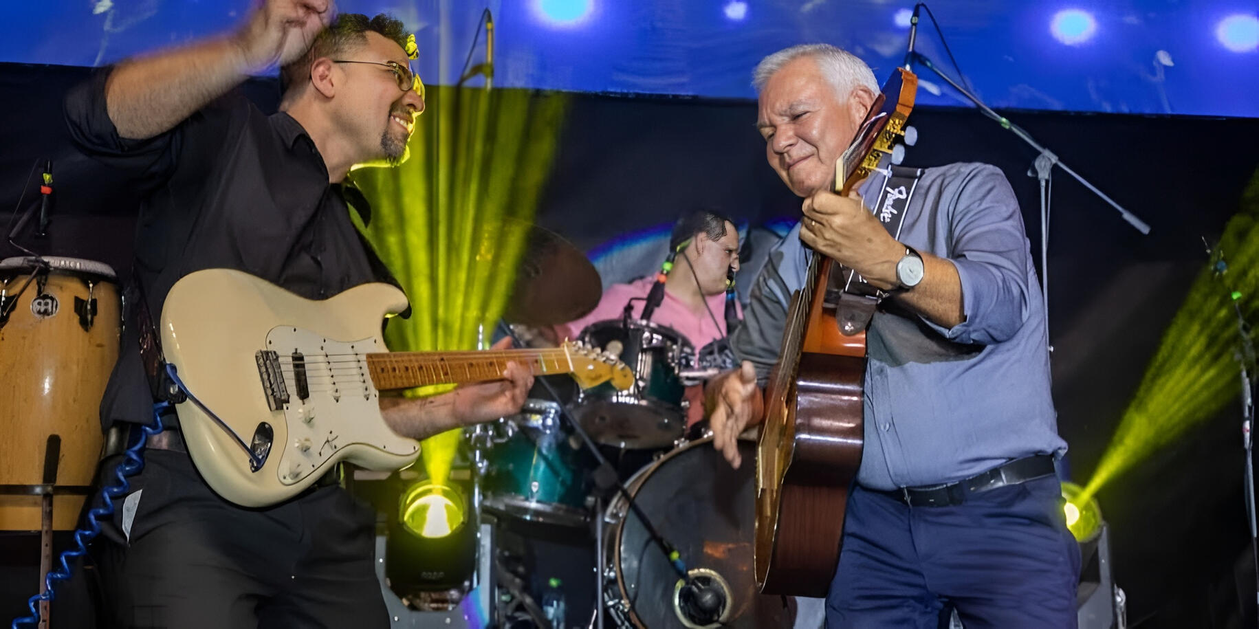 Everton Vidal playing guitar alongside Tingo Vincenti at the principal stage of Expocruz, sharing a high-energy moment with the band.